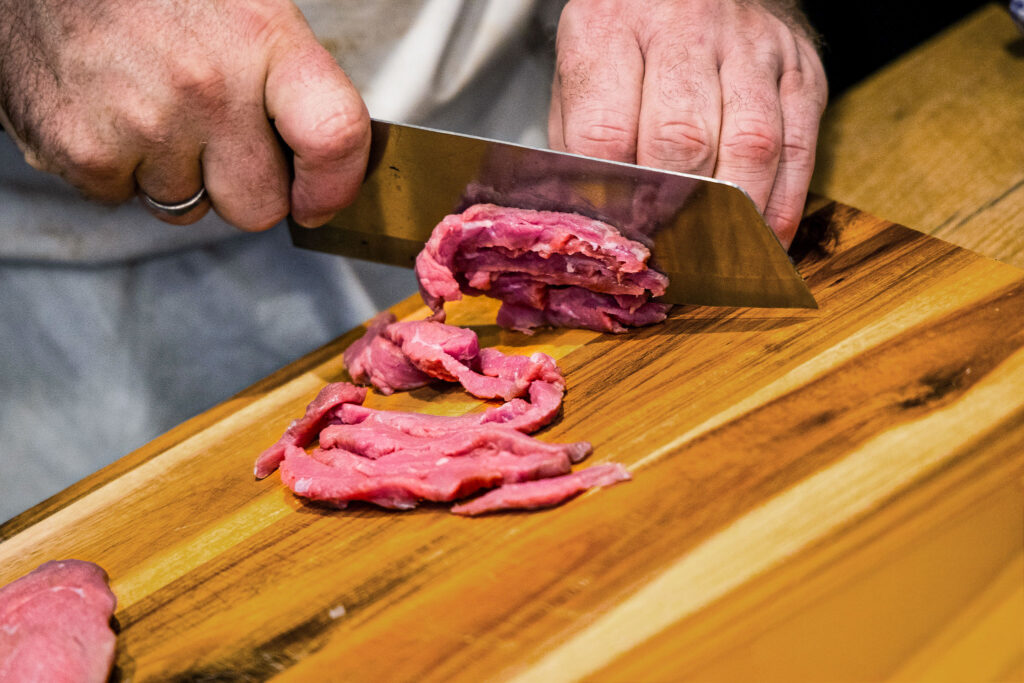 Nahaufnahme von Fleisch das mit einem Messer geschnitten wird.